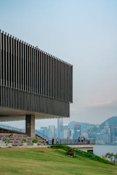 Contemporary building with skyline view of Hong Kong across the harbor.