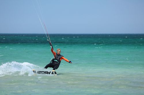 Free Man enjoying a thrilling wakeboarding session on the open ocean under bright blue skies. Stock Photo