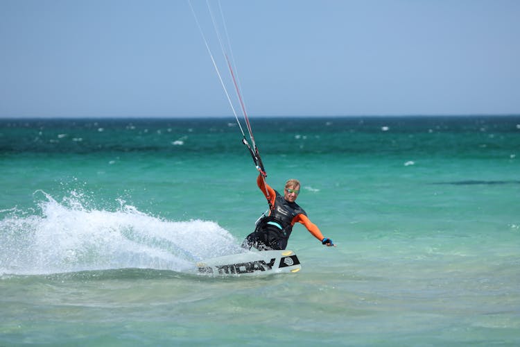 A Man Kitesurfing On Sea