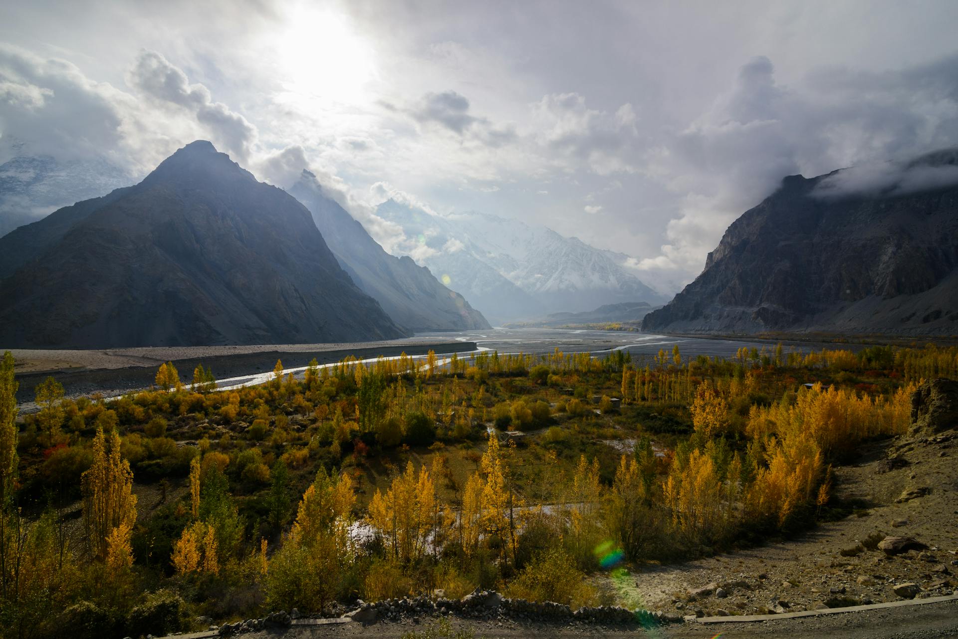 Stunning autumn view of mountain valley in Pakistan with vibrant colors and dramatic clouds.