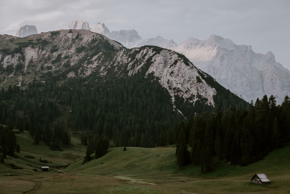 Serene mountain landscape with green valleys and dense forests under a cloudy sky.