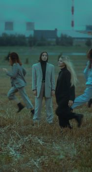 Group of women in suits standing and moving in an open field, with blurred motion effect.