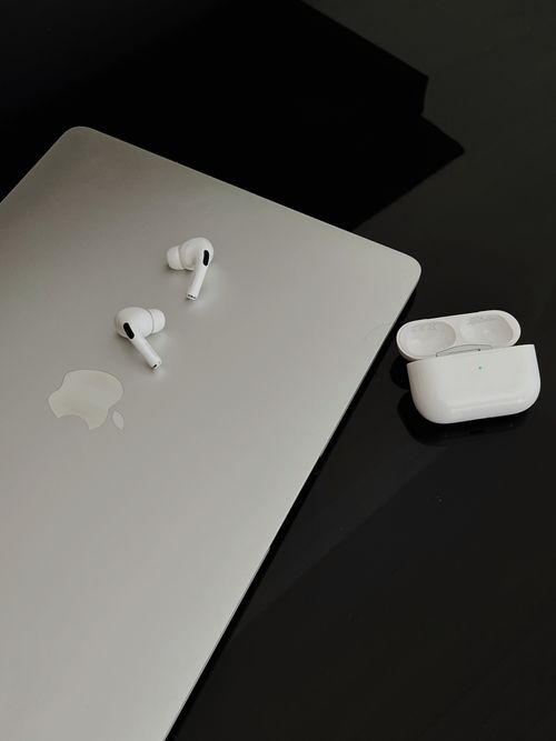 Free A sleek composition featuring AirPods Pro and MacBook on a dark surface, showcasing minimalist design. Stock Photo