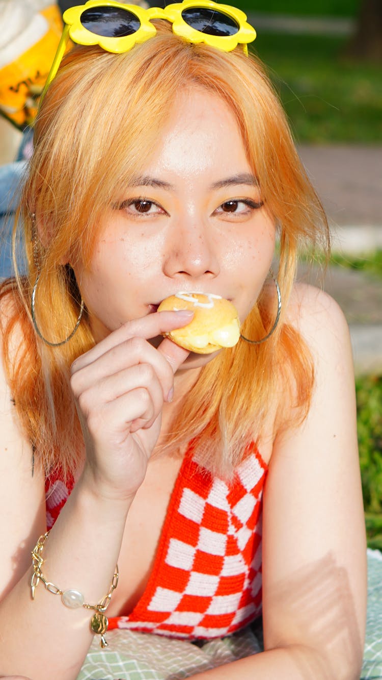 A Woman In Red And White Tank Top Eating Bread