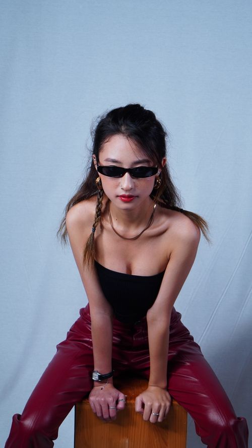 Free Fashionable young woman in studio wearing red leather pants and sunglasses. Stock Photo