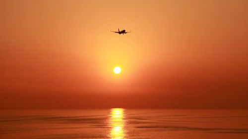 Free Airplane flying over the ocean at sunset near Istanbul, creating a stunning silhouette against the vibrant sky. Stock Photo