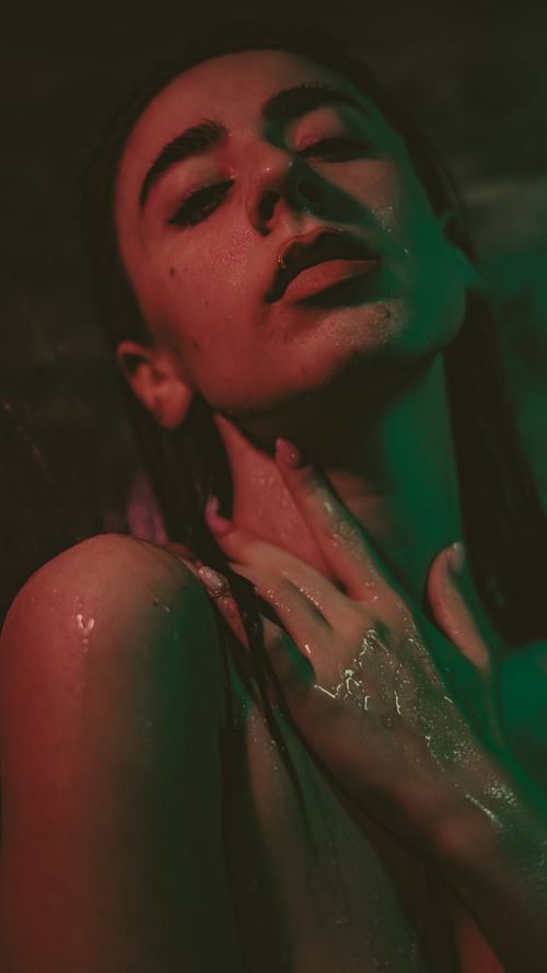 Free Close-up portrait of a woman with wet hair and sensual pose in moody lighting. Stock Photo