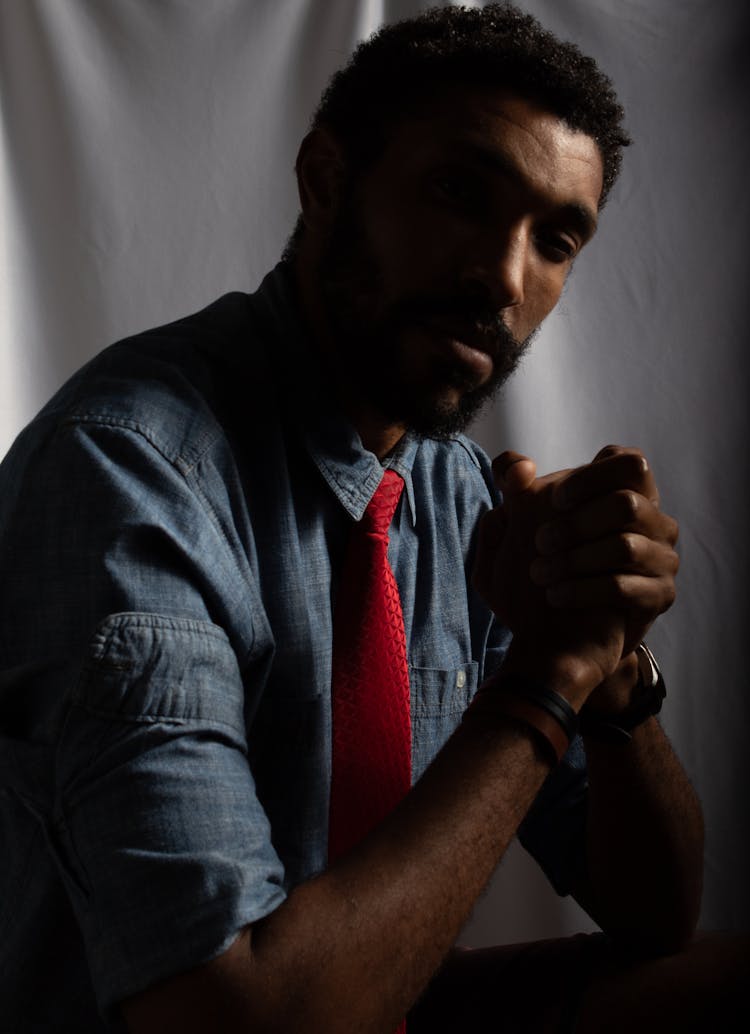 A Portrait Of A Bearded Man Wearing A Denim Top And A Red Necktie