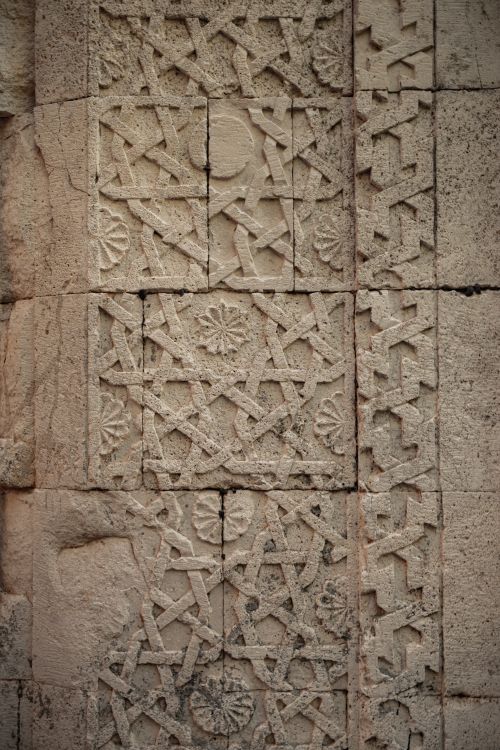 Free Detailed close-up of an ancient stone wall with intricate carvings and patterns. Stock Photo