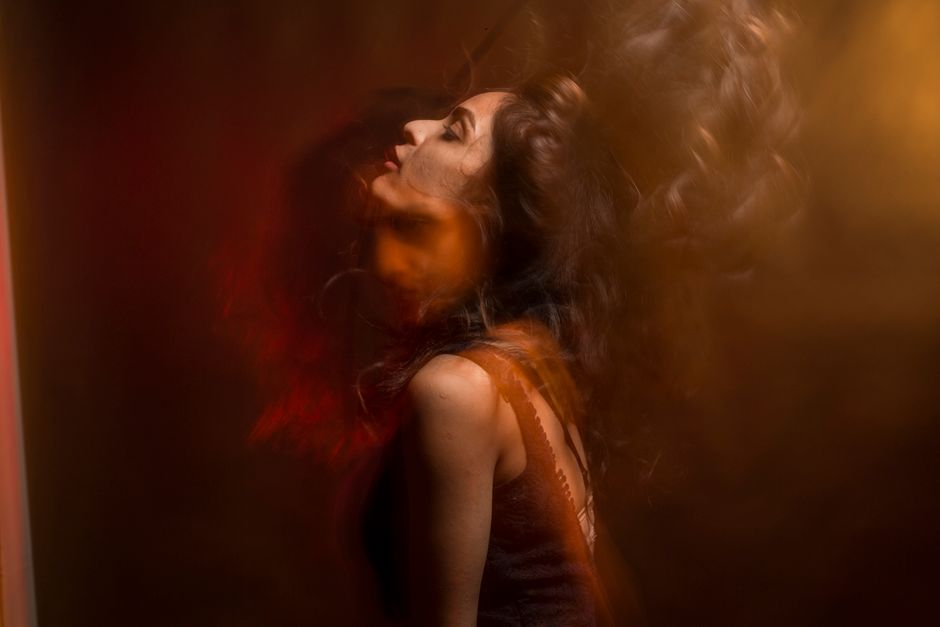Stunning long exposure portrait of a woman with blurred motion and warm lighting.