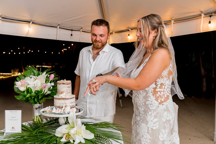 A Newlywed Couple Cutting A Cake