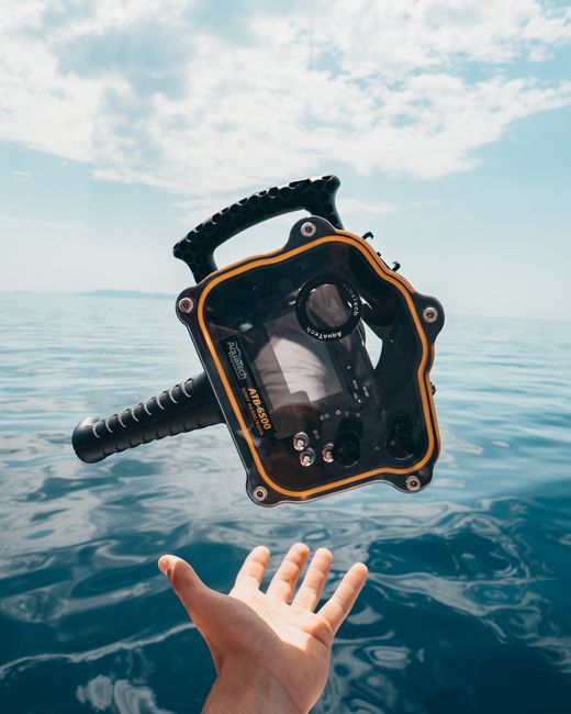 A waterproof camera case suspended mid-air over a calm ocean, capturing the essence of a sunny day at sea.