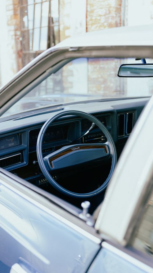 Free Interior of a classic car featuring a vintage steering wheel and dashboard. Stock Photo