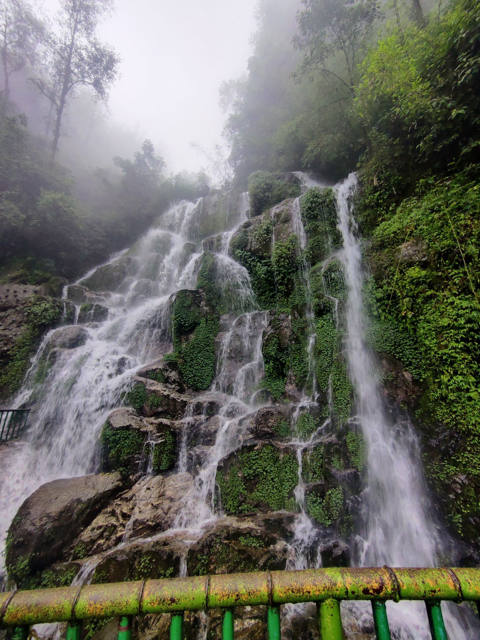 The Bakthang waterfall near Gangtok, water spreading over mossy green rock on a misted Sikkim hillside
