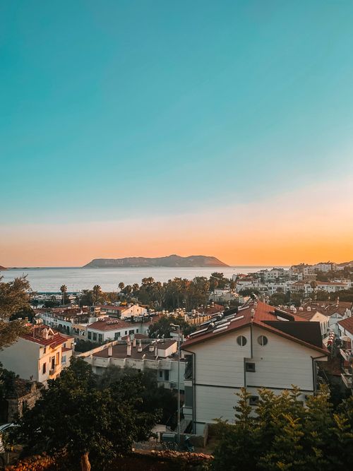 Free A breathtaking view of Antalya's cityscape with a golden sunset over the sea, capturing the serene beauty of the Turkish coast. Stock Photo