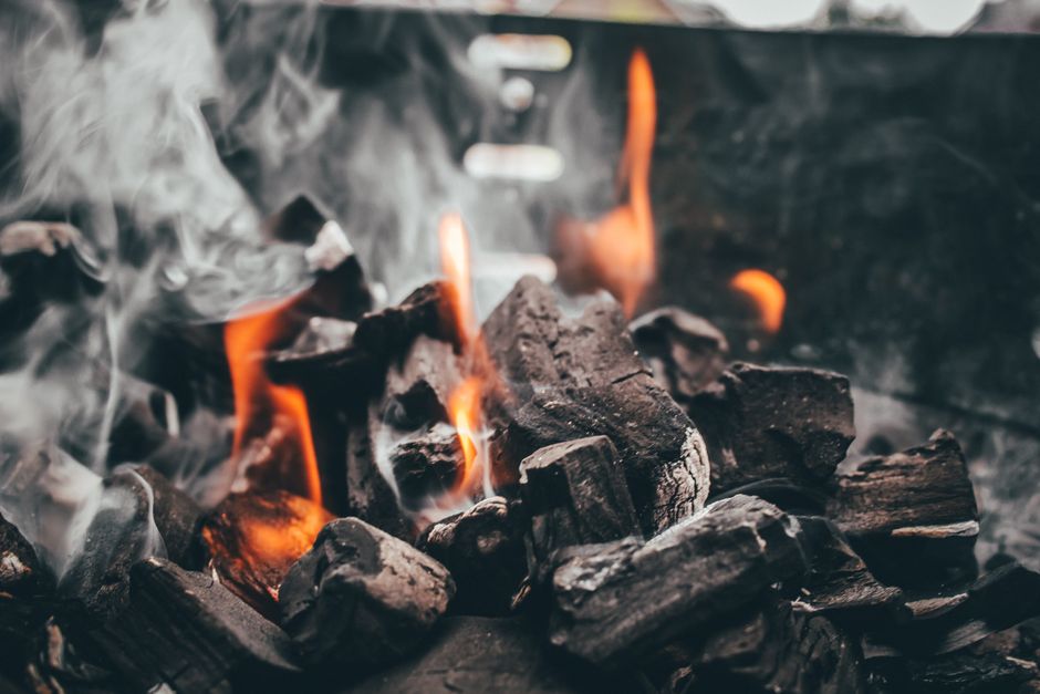 Captivating close-up of charcoal engulfed in flames and smoke, creating a fiery display.