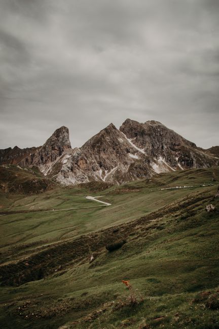 A stunning mountain landscape with rugged peaks and lush green hills under a cloudy sky.