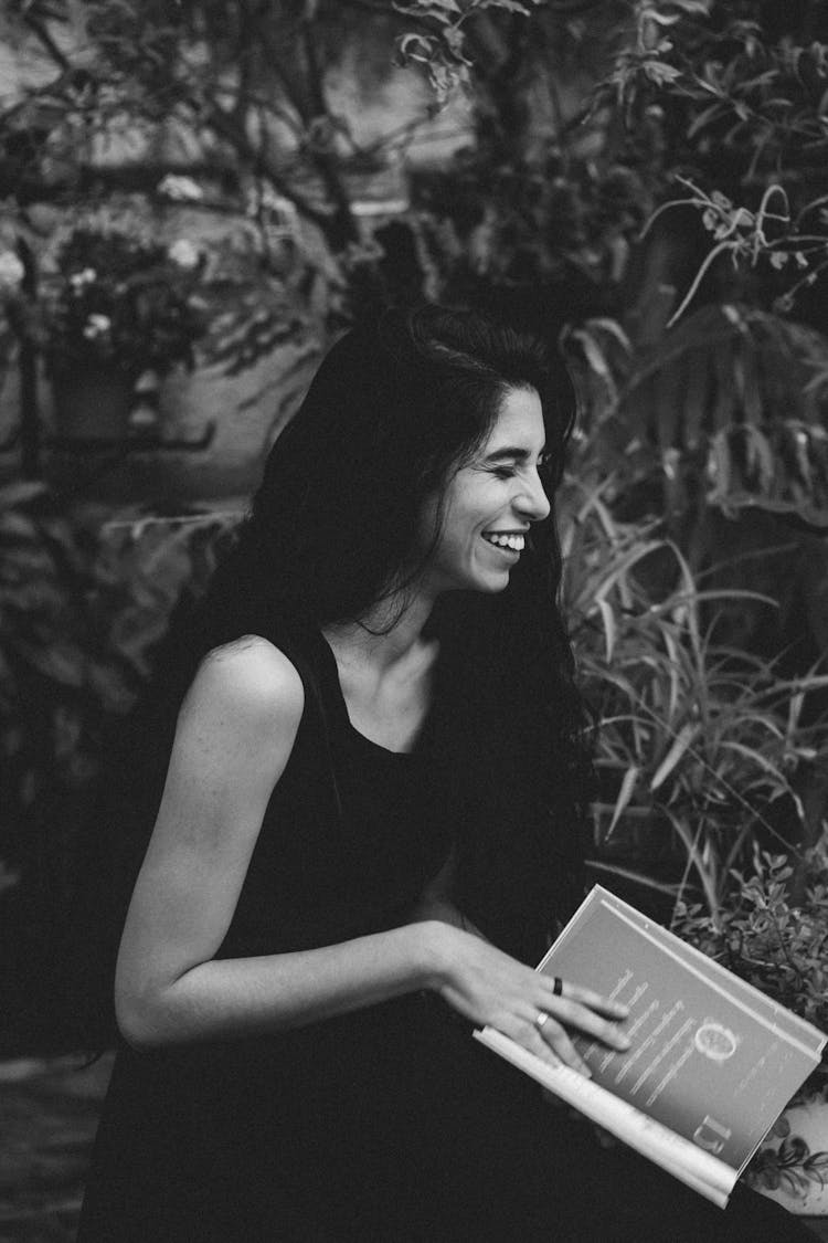 Smiling Woman Reading Book In Garden