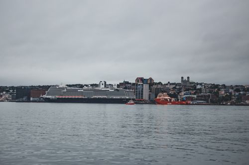 Free City harbor view featuring a large cruise ship, skyline, and calm sea under overcast skies. Stock Photo