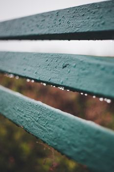 Close-up shot of a wooden fence with raindrops on a blurred background.