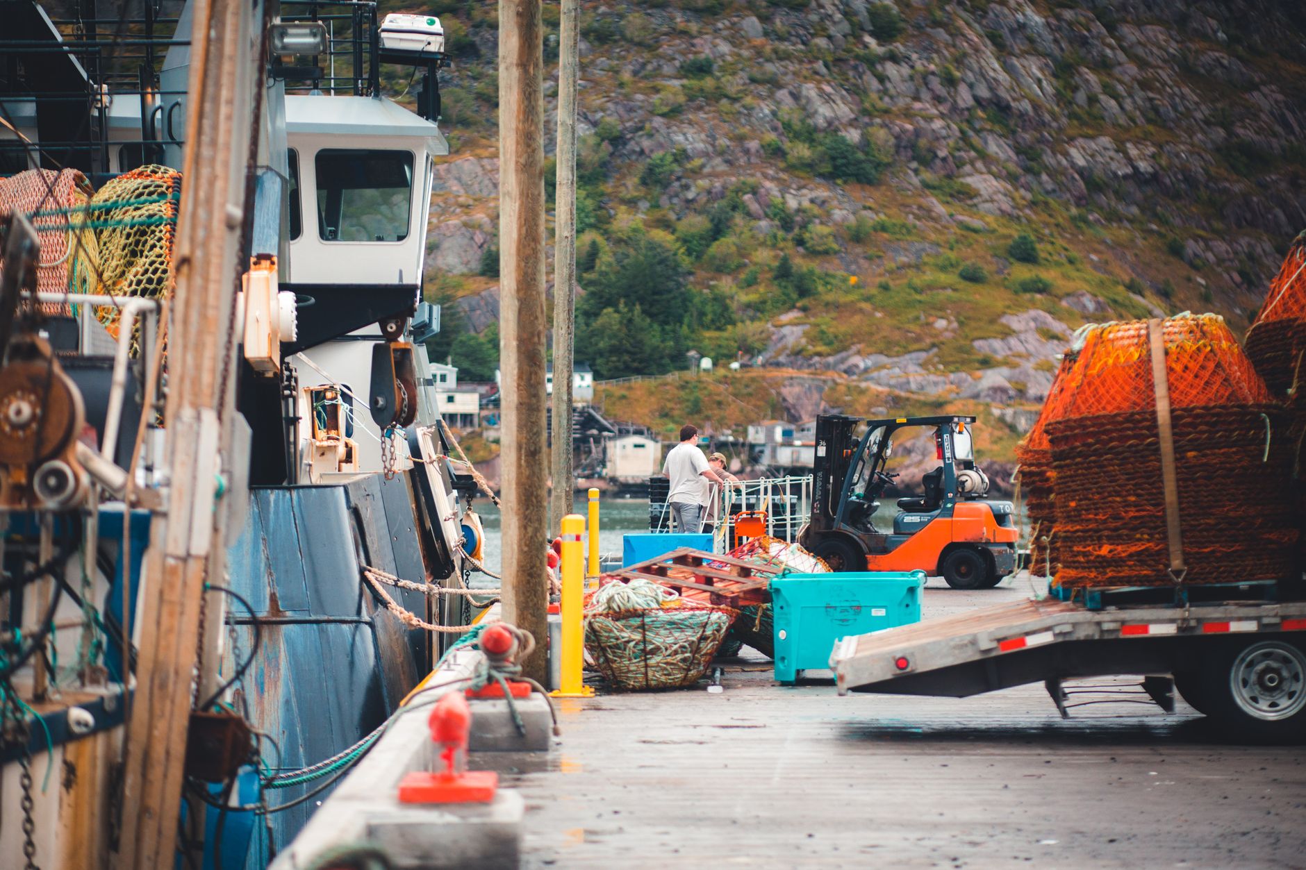 A vibrant port scene featuring a fishing boat, forklift, and fishing equipment, showcasing harbor activity.