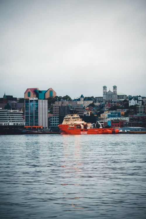 Free A bustling harbor with colorful buildings and a vibrant cityscape reflecting on calm waters. Stock Photo