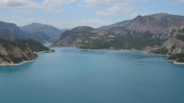 A breathtaking aerial shot of a serene lake surrounded by mountains on a clear day.