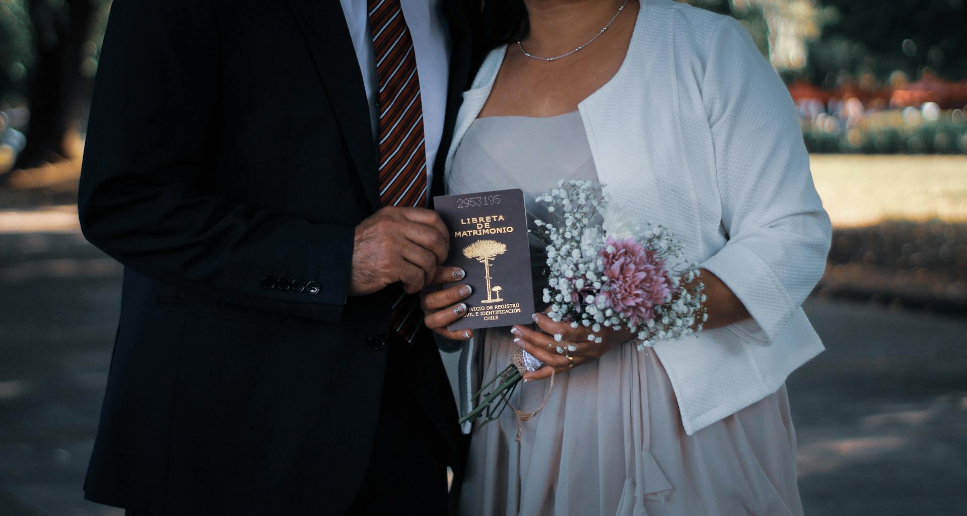 Woman and Man Holding Bouquet and Marriage Certificate