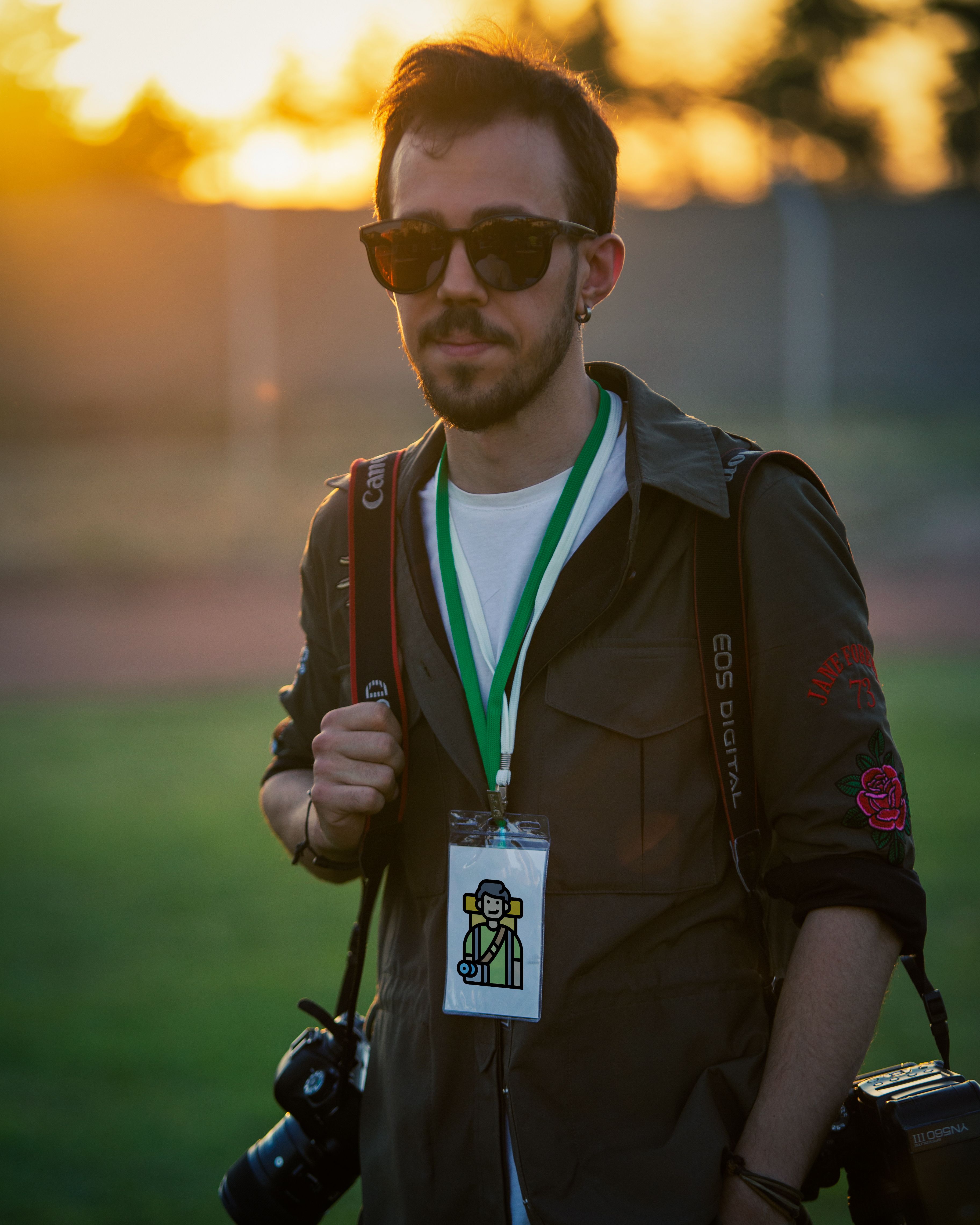 A stylish photographer holding a camera, capturing the golden sunset outdoors.