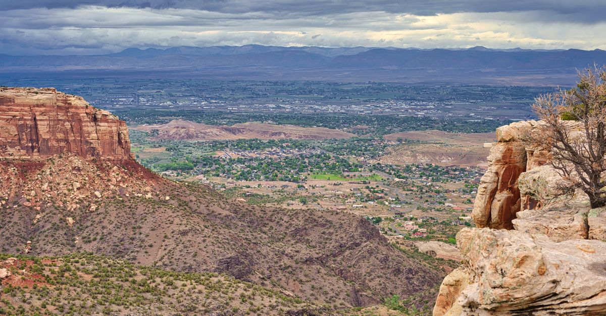 Breathtaking view of Monument Canyon with expansive desert panorama and dramatic clouds.