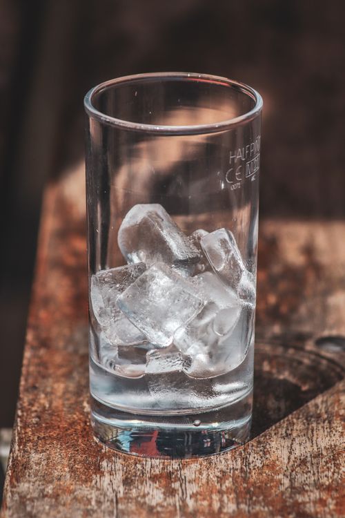 Free A close-up view of clear ice cubes in a glass on a rustic wooden surface, showcasing texture and simplicity. Stock Photo