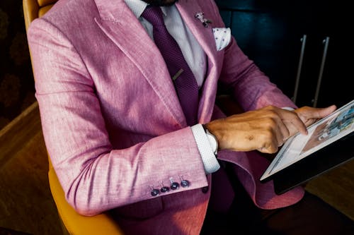Mann, Der Rosa Anzug Jacken Halten Unter Verwendung Des Tablet Computers Trägt