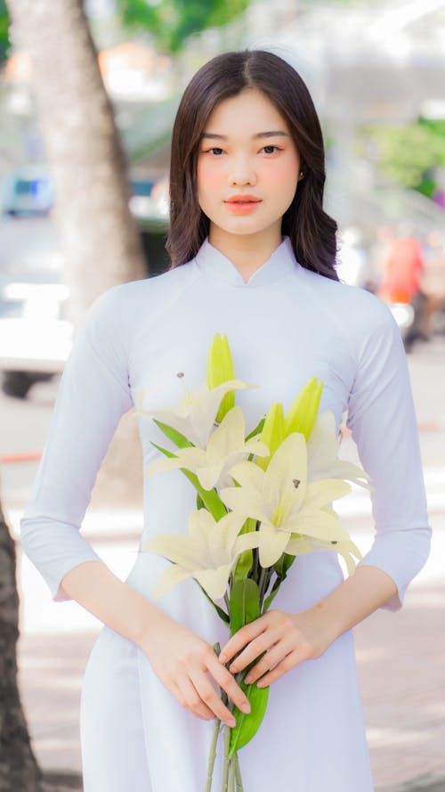 Beautiful Woman in White Long Sleeve Dress Holding White Flowers