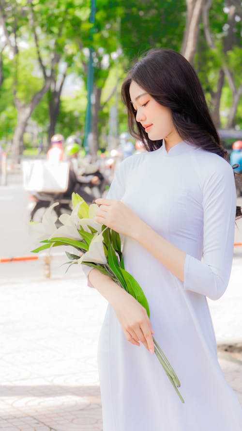 Beautiful Woman in White Traditional Dress Holding Flowers