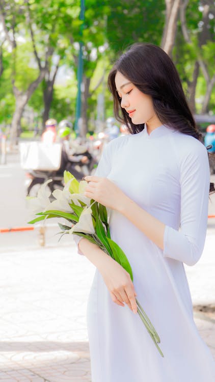 Gratis arkivbilde med ao dai, asiatisk kvinne, holder blomster