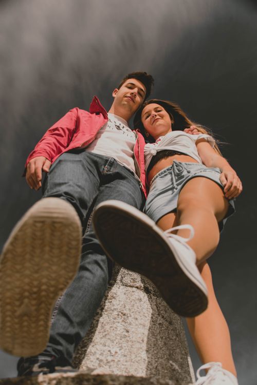 Free Low angle shot of a young couple in casual attire standing against a dark summer sky in Fátima, Portugal. Stock Photo