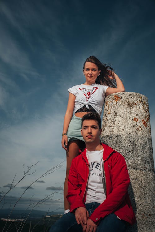 Free Woman in Red and White Crew Neck T-shirt Standing Beside Brown and Gray Rock Stock Photo