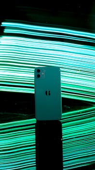 Artistic shot of a smartphone against a vibrant neon light background.