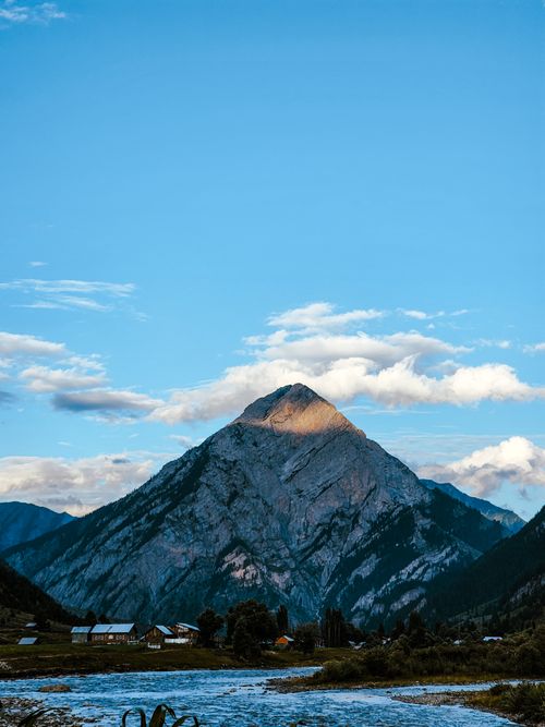 Free Scenic view of a mountain under a bright blue sky with fluffy clouds, offering a serene landscape. Stock Photo