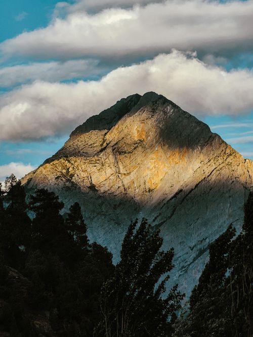 Free A majestic rocky mountain with dramatic clouds and sunlight creating beautiful contrast. Stock Photo