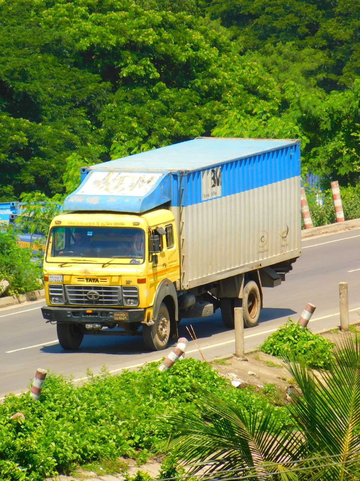 Cargo lorry driving in strong sunlight on a tropical highway — the daily UV exposure that sets lorry sticker service life