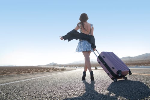 Free Female Hitchhiking on Highway with Suitcase Stock Photo