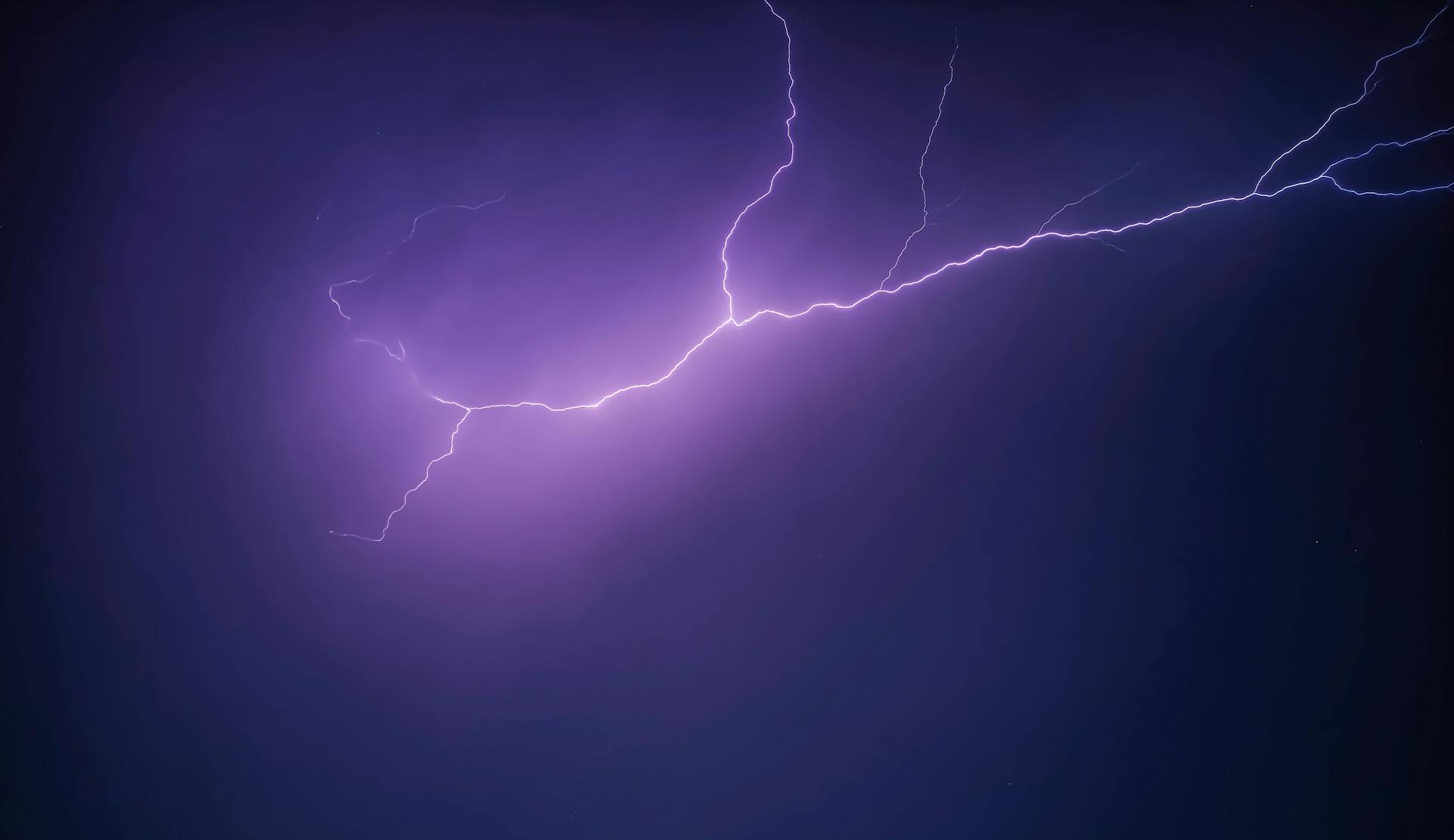 A striking image of a purple lightning bolt illuminating the night sky, creating a dramatic and moody scene.
