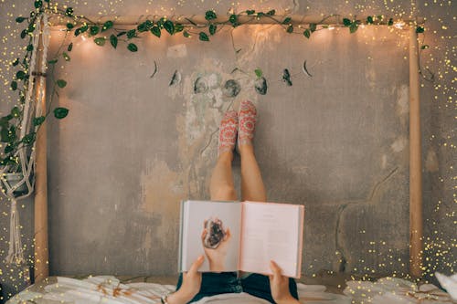 Person Reading a Book While Lying on Bed 