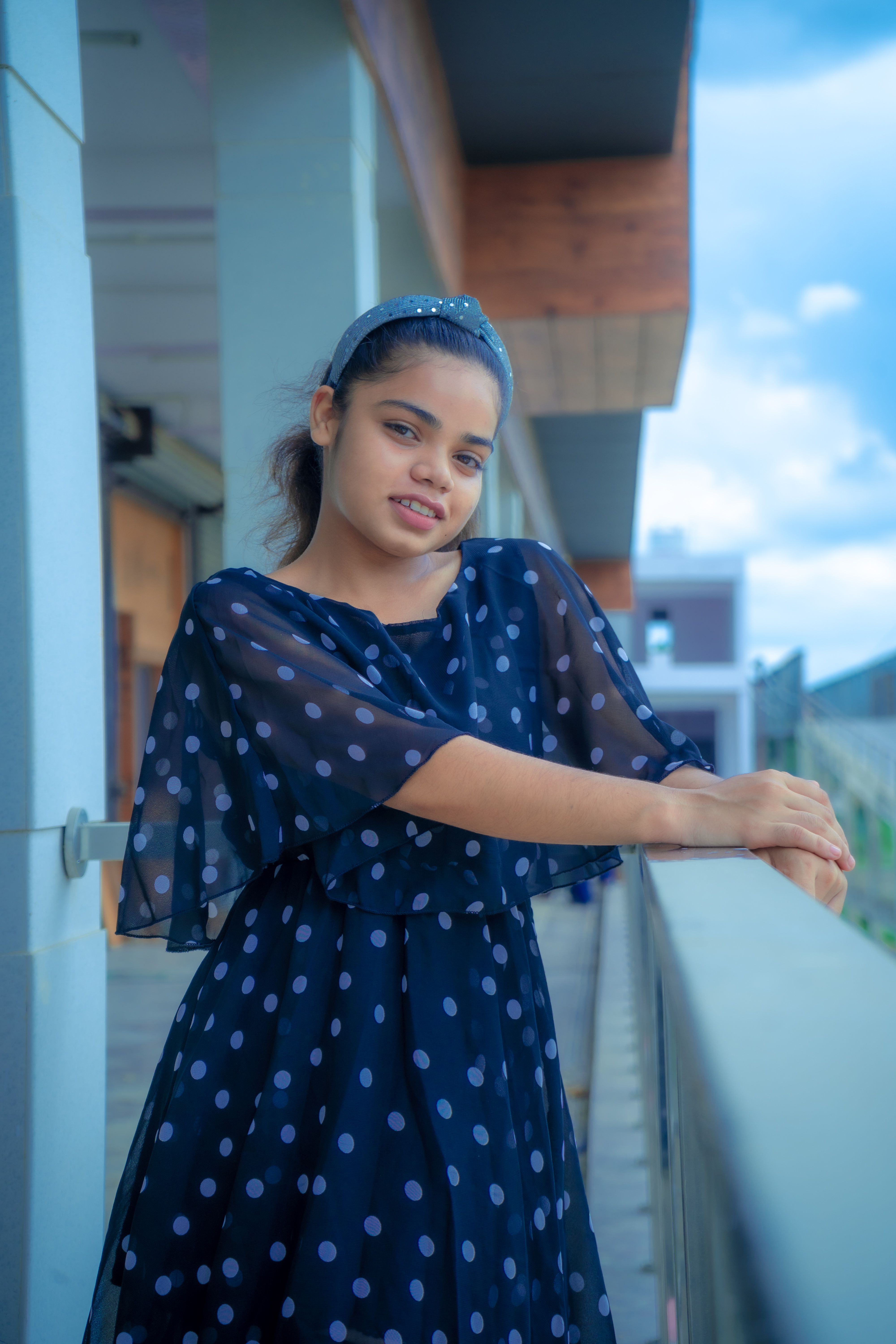 A Girl in Blue and White Polka Dot Dress Standing Beside the Metal ...