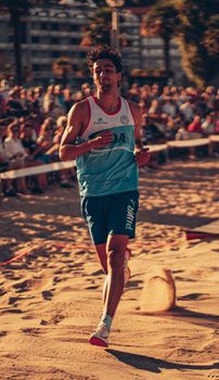 Man running energetically on a beach during a sports event in Sada, Spain.
