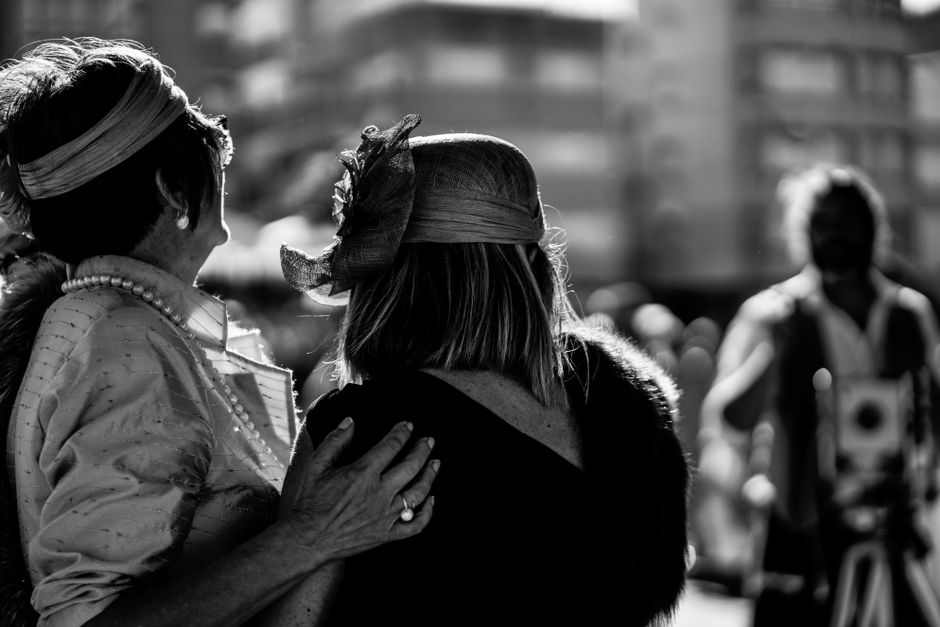 Dos mujeres mayores con estilo, usando sombreros vintage y perlas, disfrutando de un entorno al aire libre en blanco y negro.