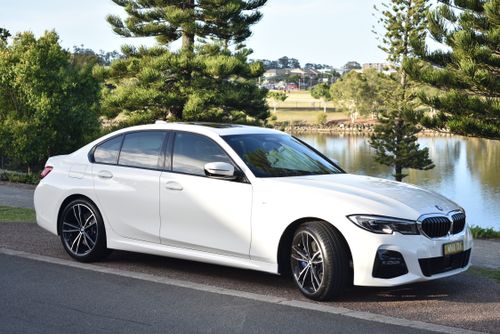 Free White BMW parked by a lakeside with trees, capturing luxury and tranquility. Stock Photo