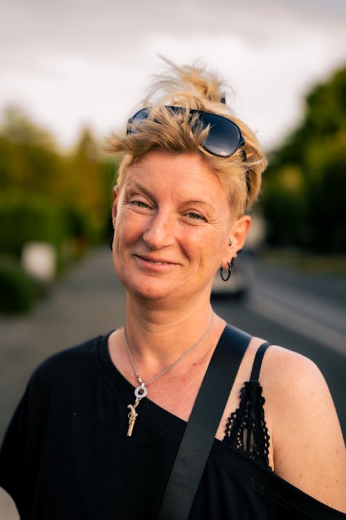 A Woman in Black Top Smiling while Wearing Sunglasses on Her Head