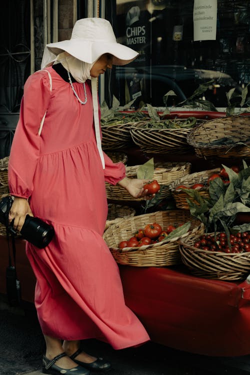 Woman in Pink Dress Looking at the Fruits